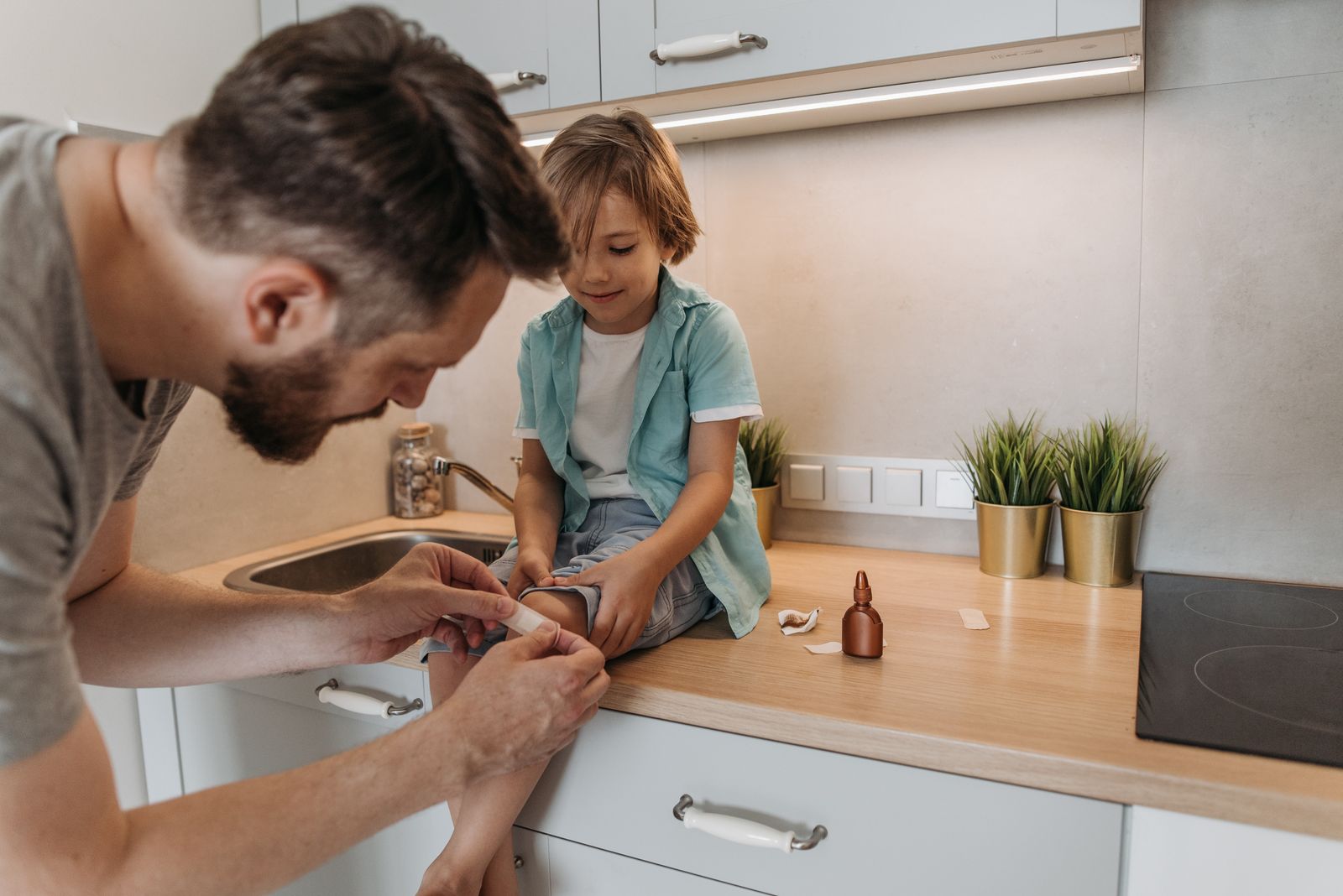 A father calmly putting a bandage on his son's leg at home