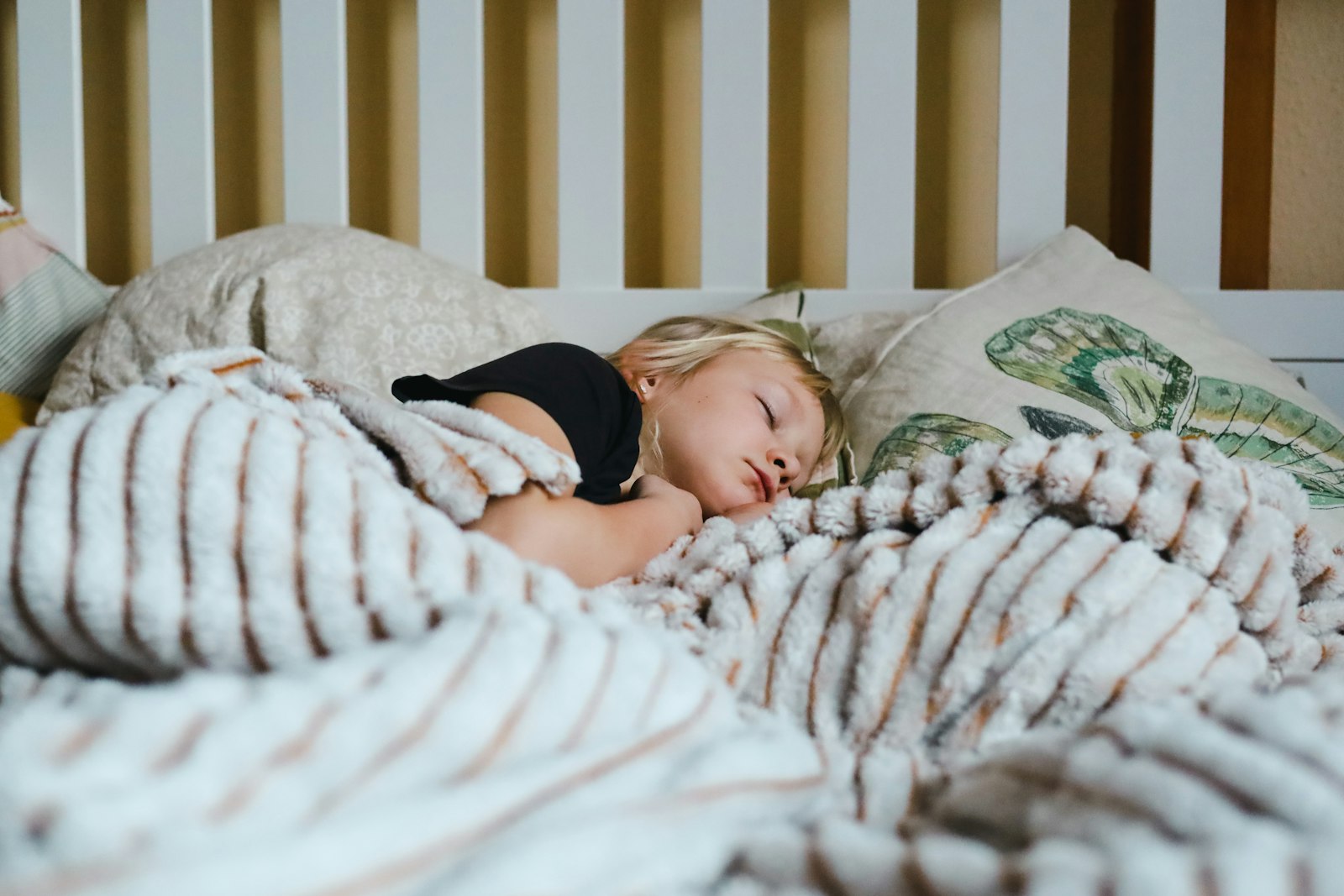 A young child sleeping peacefully, wrapped in a cozy blanket