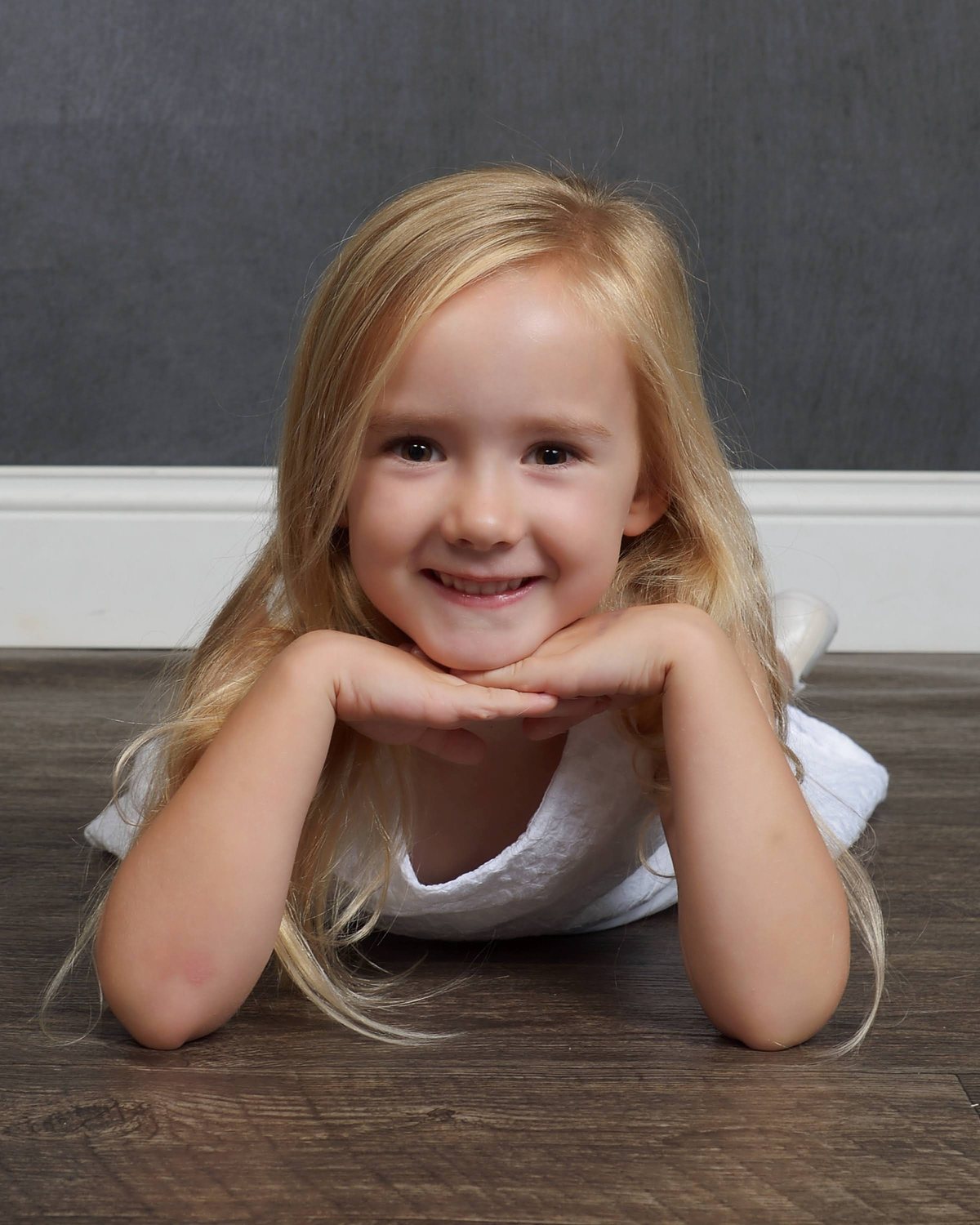 A smiling young girl resting her chin on her hands