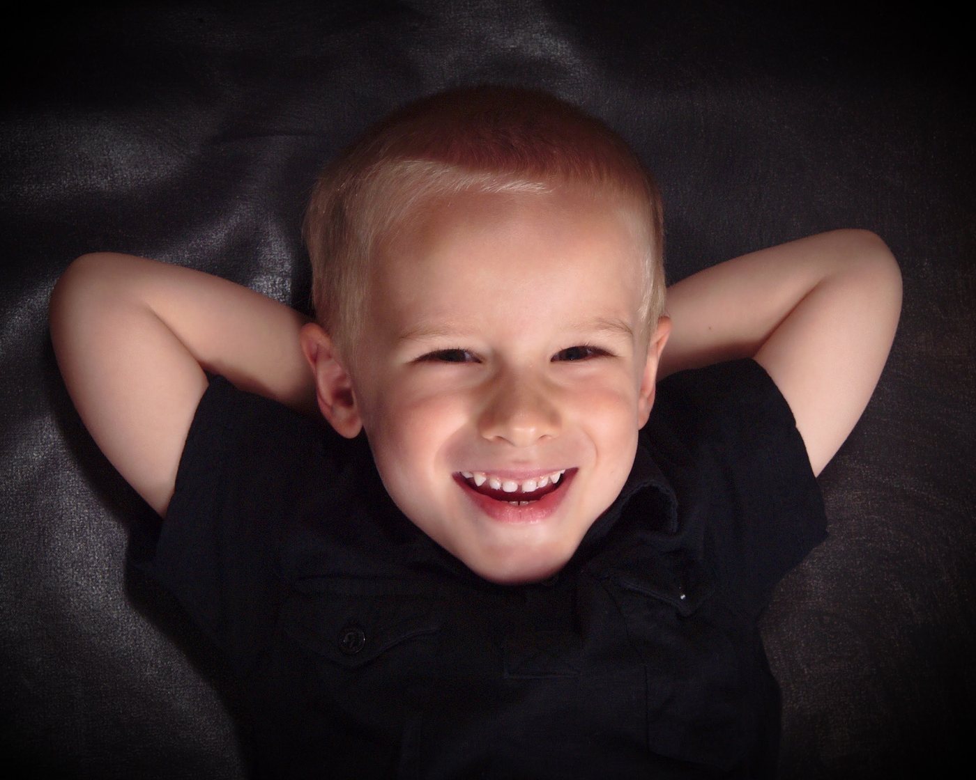 A laughing young boy lying with his hands behind his head