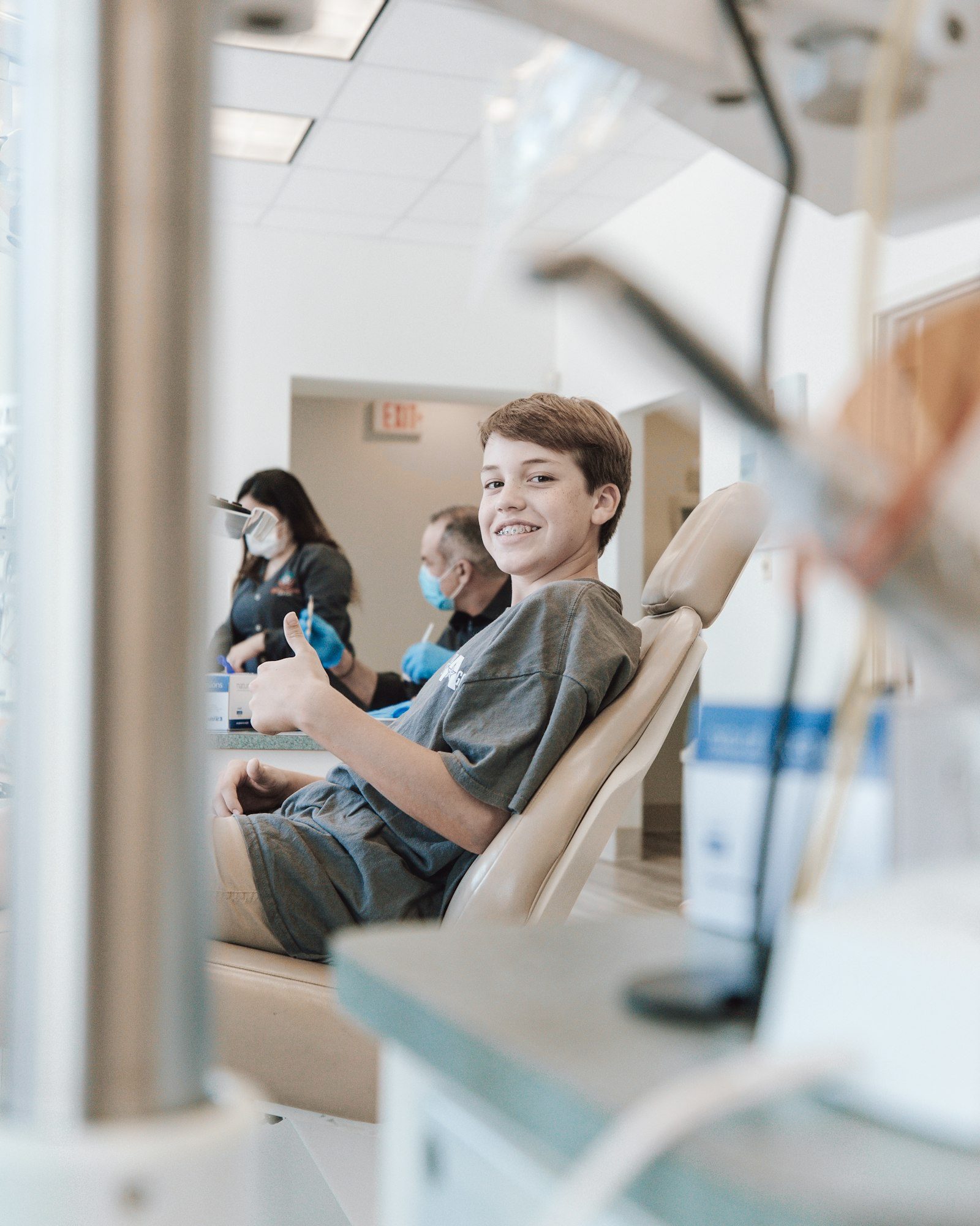 A smiling young patient giving a thumbs up in the chair at a modern pediatric dental office